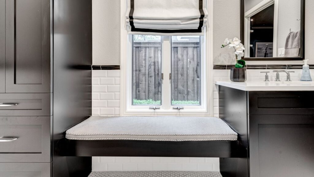 Contemporary bathroom with black cabinetry, white subway tiles, a window with a bench seat, and modern fixtures.