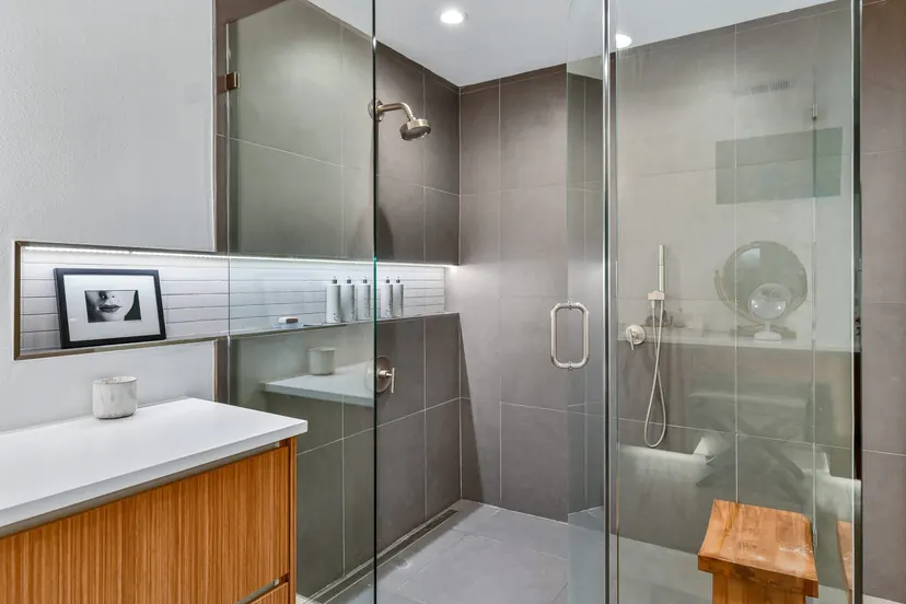 Carrollton bathroom remodel idea: glass walk-in shower in dark tile with a teak bench and a wood vanity