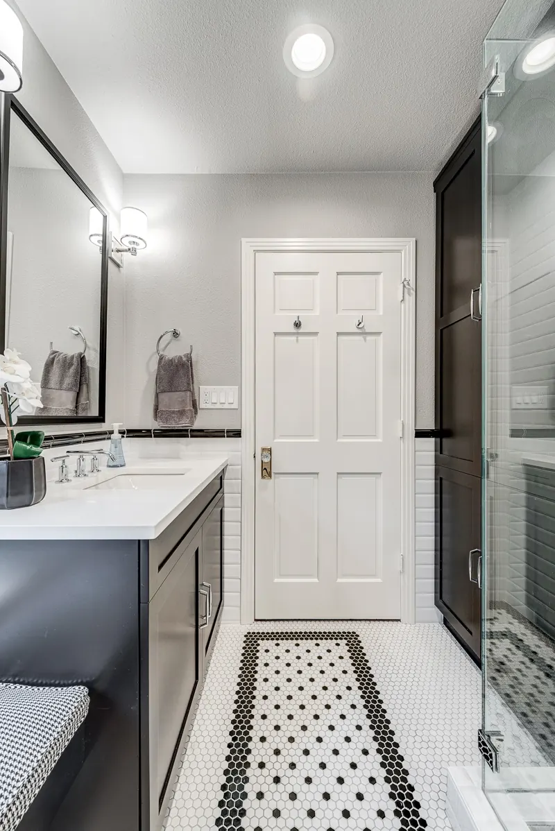 Grapevine bathroom remodel idea: dark vanity, framed mirror and a black and white mosaic floor