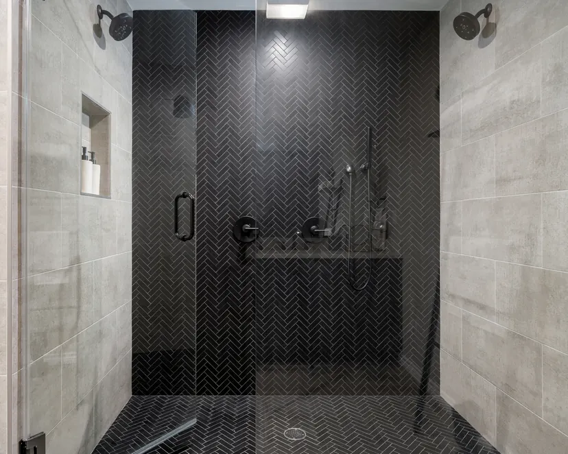 Highland Village bathroom remodel idea: double shower in black herringbone tile with a built-in bench