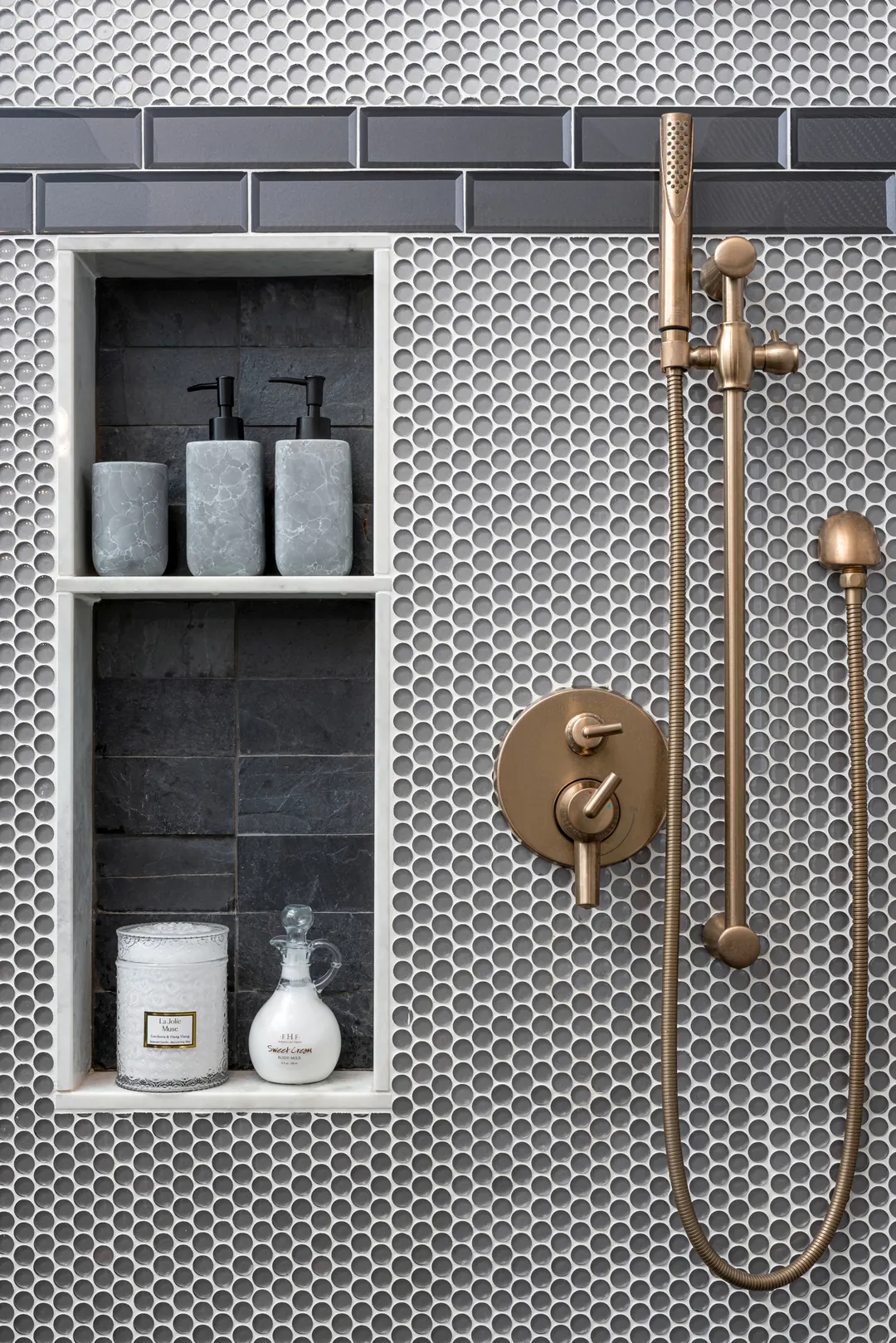 Frisco shower by Nomi in gray penny tile with a recessed niche and brushed brass fixtures