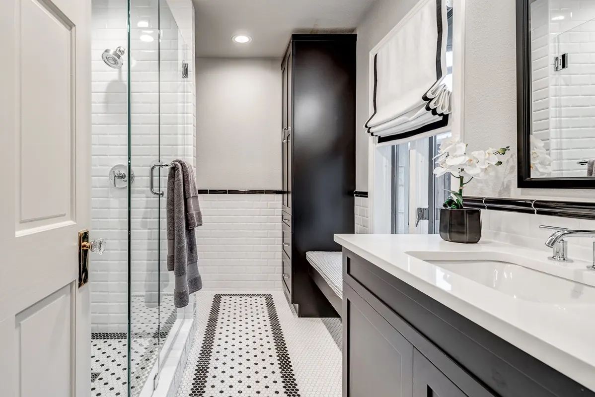 Prosper bathroom by Nomi with a glass walk-in shower, white subway tile with a black liner and a dark vanity